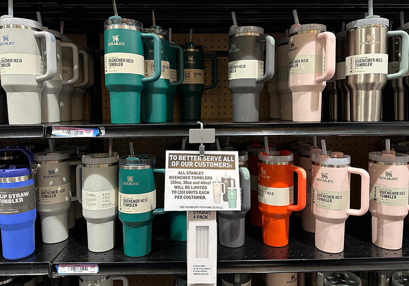 Two black shelves packed with multi colour Stanley Tumbler Quenchers with a sign saying "limit to 20 tumblers can be purchased at a time"
